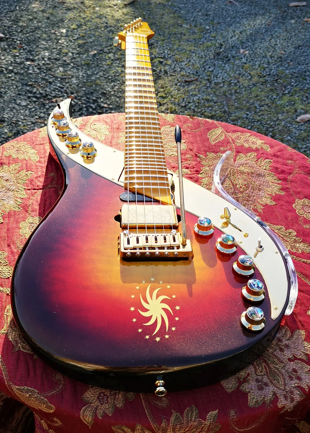 Sunrise Sky de la serie Sky Elite, acabado sunburst y placa espejada, sobre una tela roja al aire libre