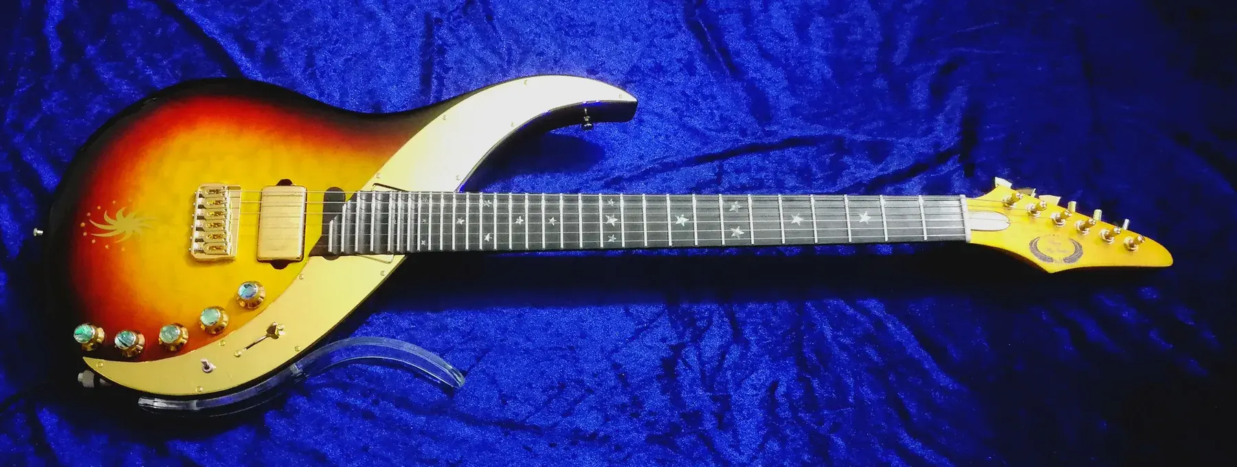 Ebony Sky sunburst completa sobre terciopelo azul, con golpeador dorado en media luna