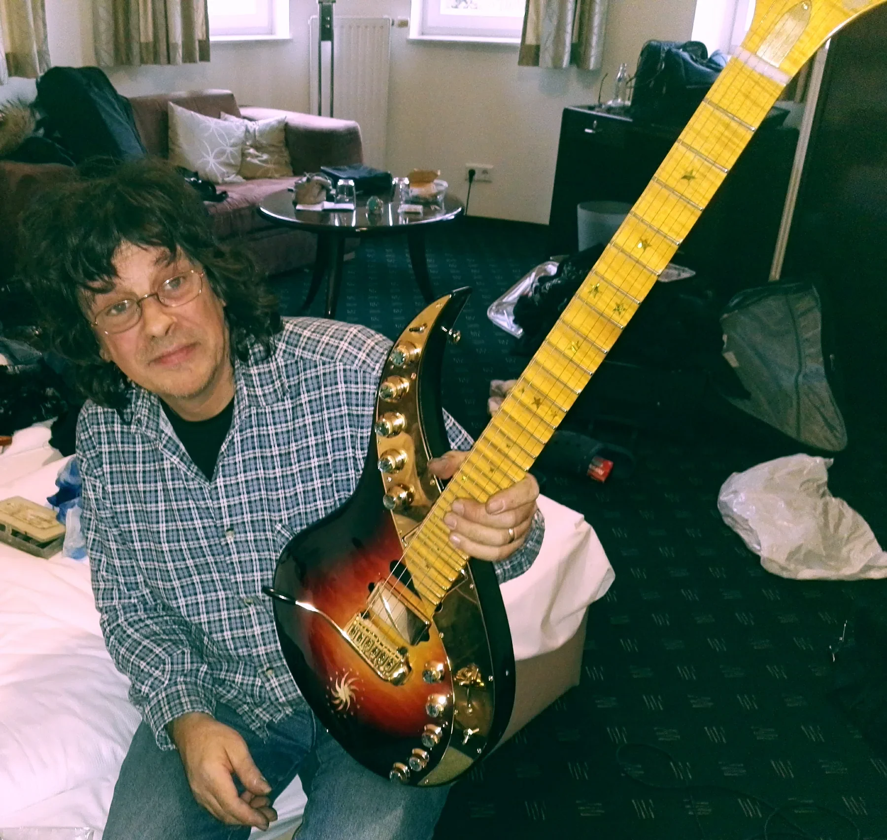 El luthier Boris Dommenget sentado con una Sky Guitar sunburst de mástil largo en las manos