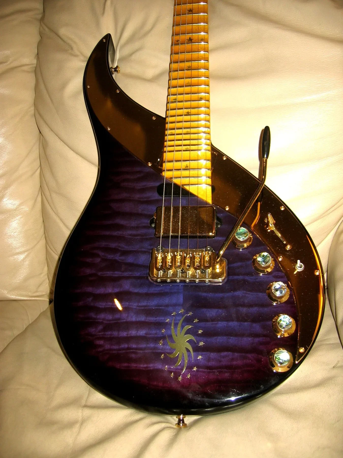 Cuerpo morado acolchado de una Sky Guitar de la serie Lionheart con sol grabado y mandos dorados