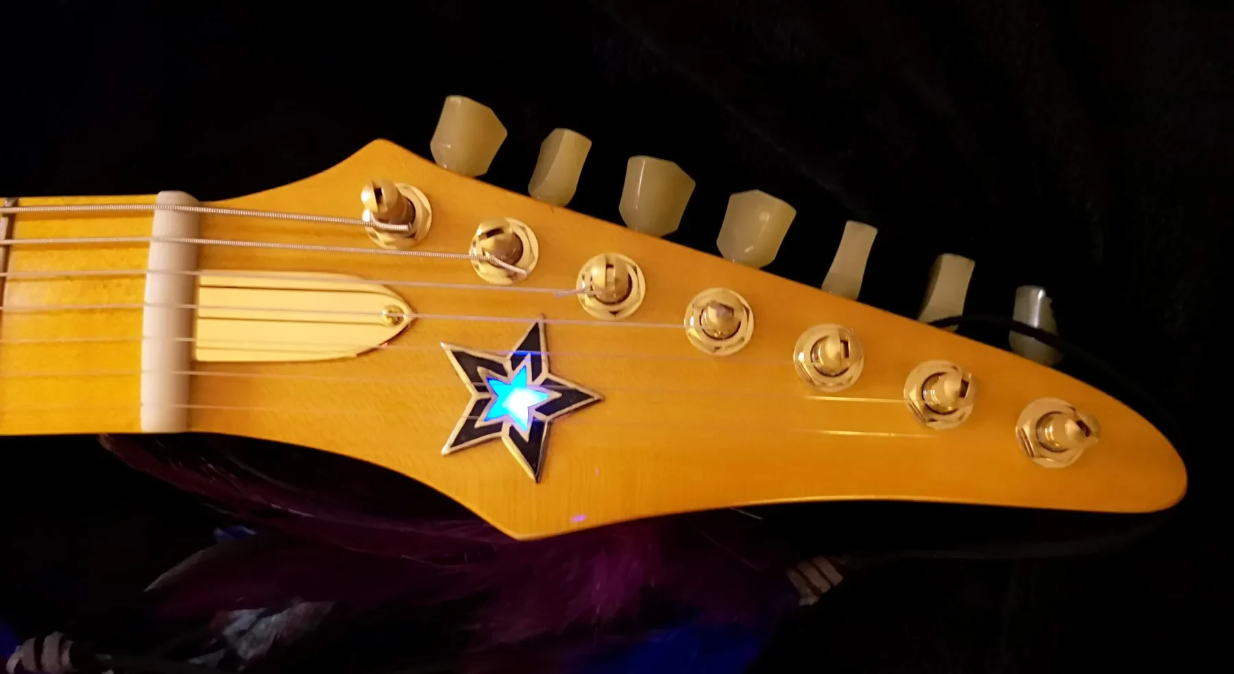 Pala dorada de la Excalibur con una estrella iluminada en azul y clavijas de botón crema