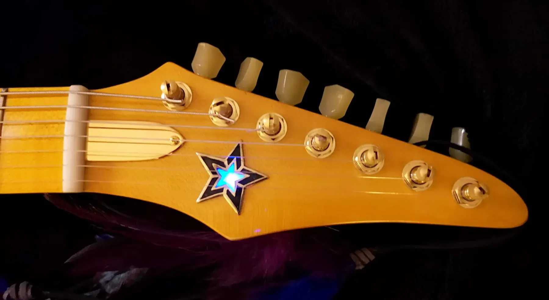 Pala dorada de la Excalibur con una estrella iluminada en azul y clavijas de botón crema