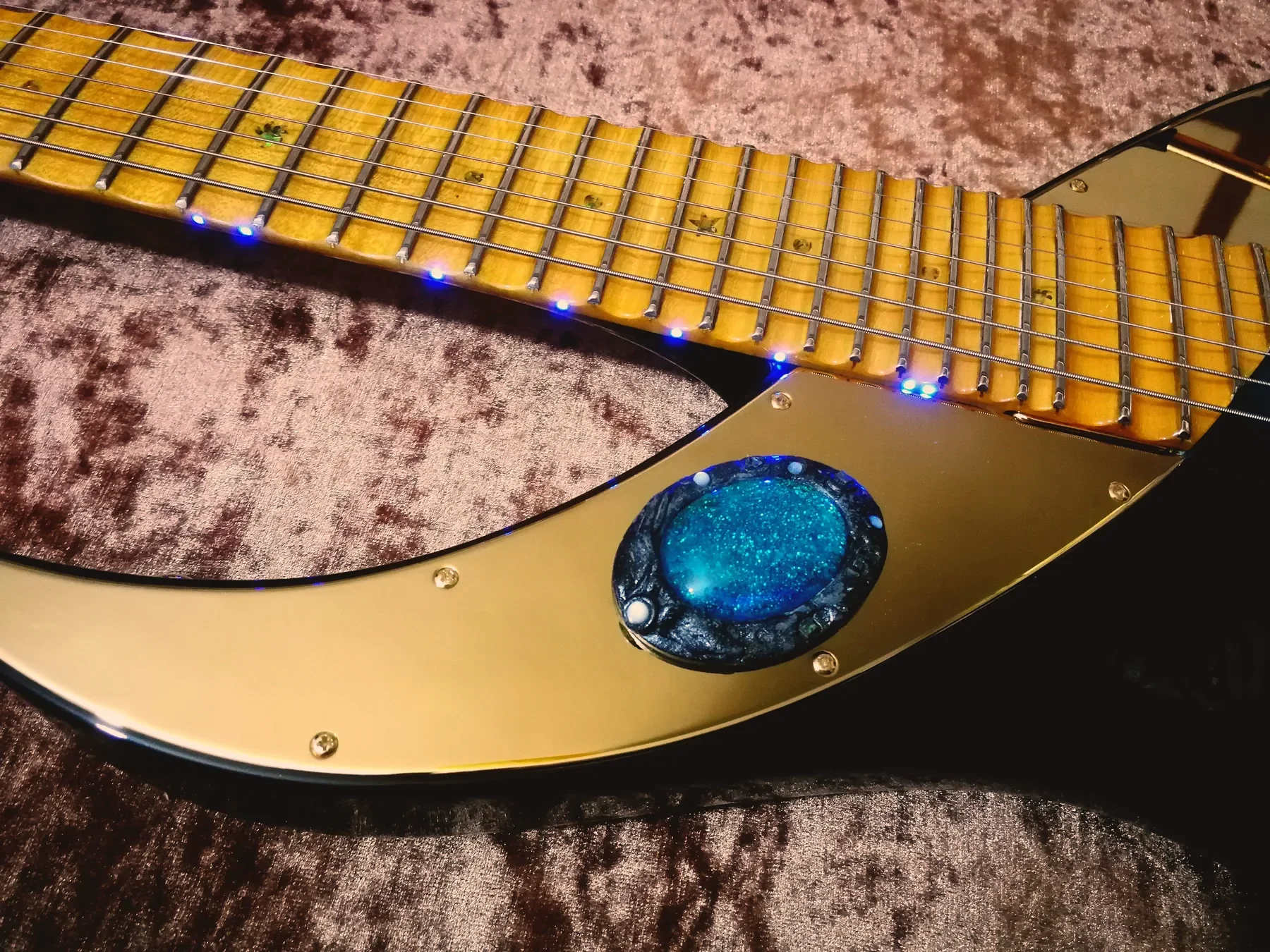 Diapasón con LED azules en el canto y broche turquesa junto a la placa dorada de la Mighty Wing II