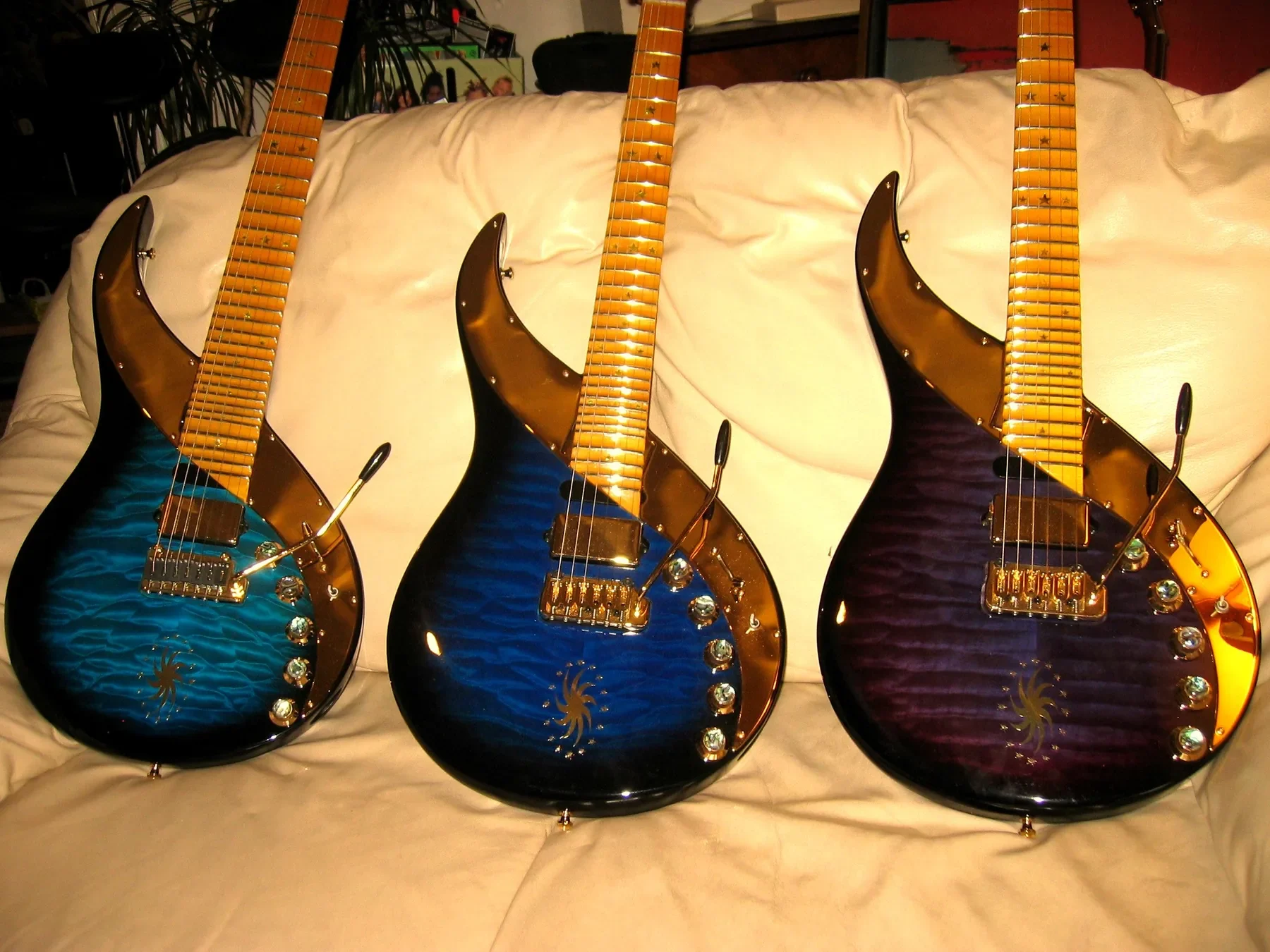 Tres Sky Guitars de la serie Lionheart en azul y morado apoyadas en un sofá blanco