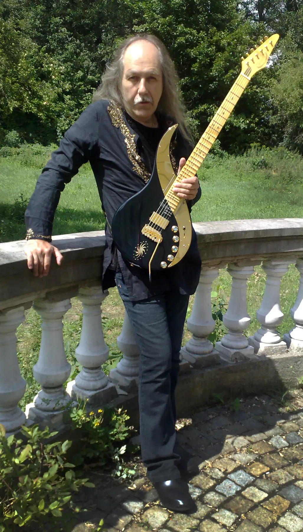 Uli Jon Roth junto a una balaustrada con la Sky Guitar negra «Black Lion Sky», julio de 2011