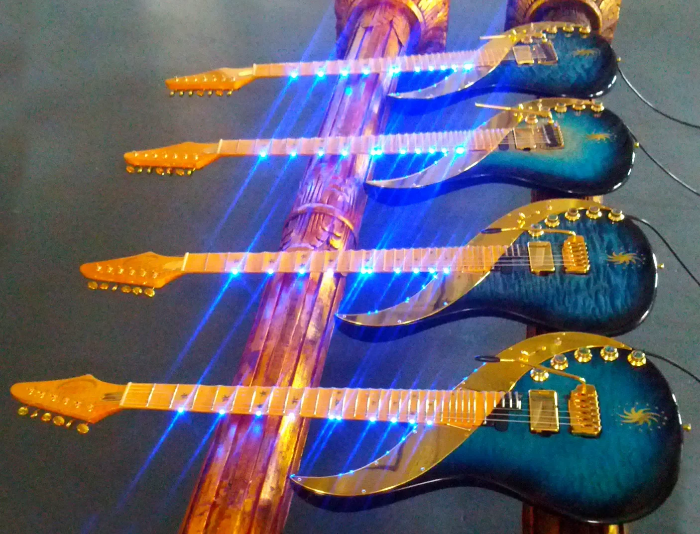 Cuatro Sky Guitars azules colgadas en fila con los LED del mástil encendidos, en Tronical en 2012