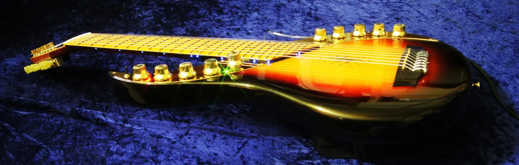 Perfil de la Sunset Sky de ocho cuerdas tumbada sobre terciopelo azul, con los mandos dorados