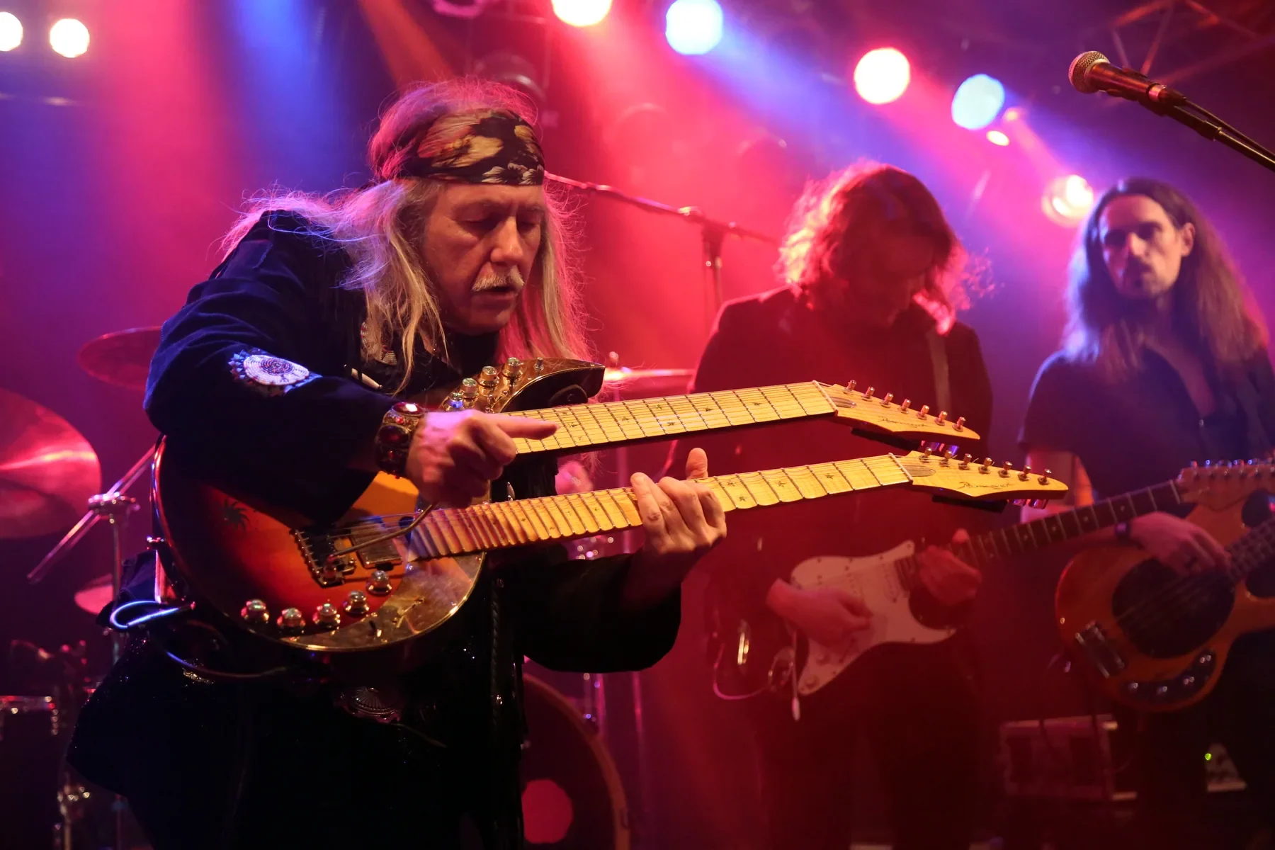 Uli Jon Roth con la Mighty New Dawn en el escenario, con dos músicos de su banda detrás