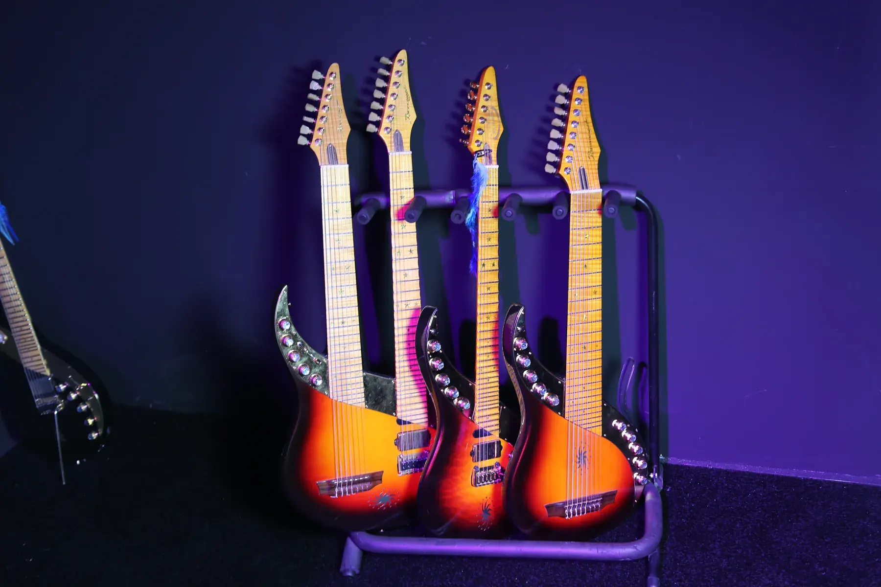 Cuatro Sky Guitars sunburst en un soporte múltiple, con las palas hacia arriba, bajo luz azul
