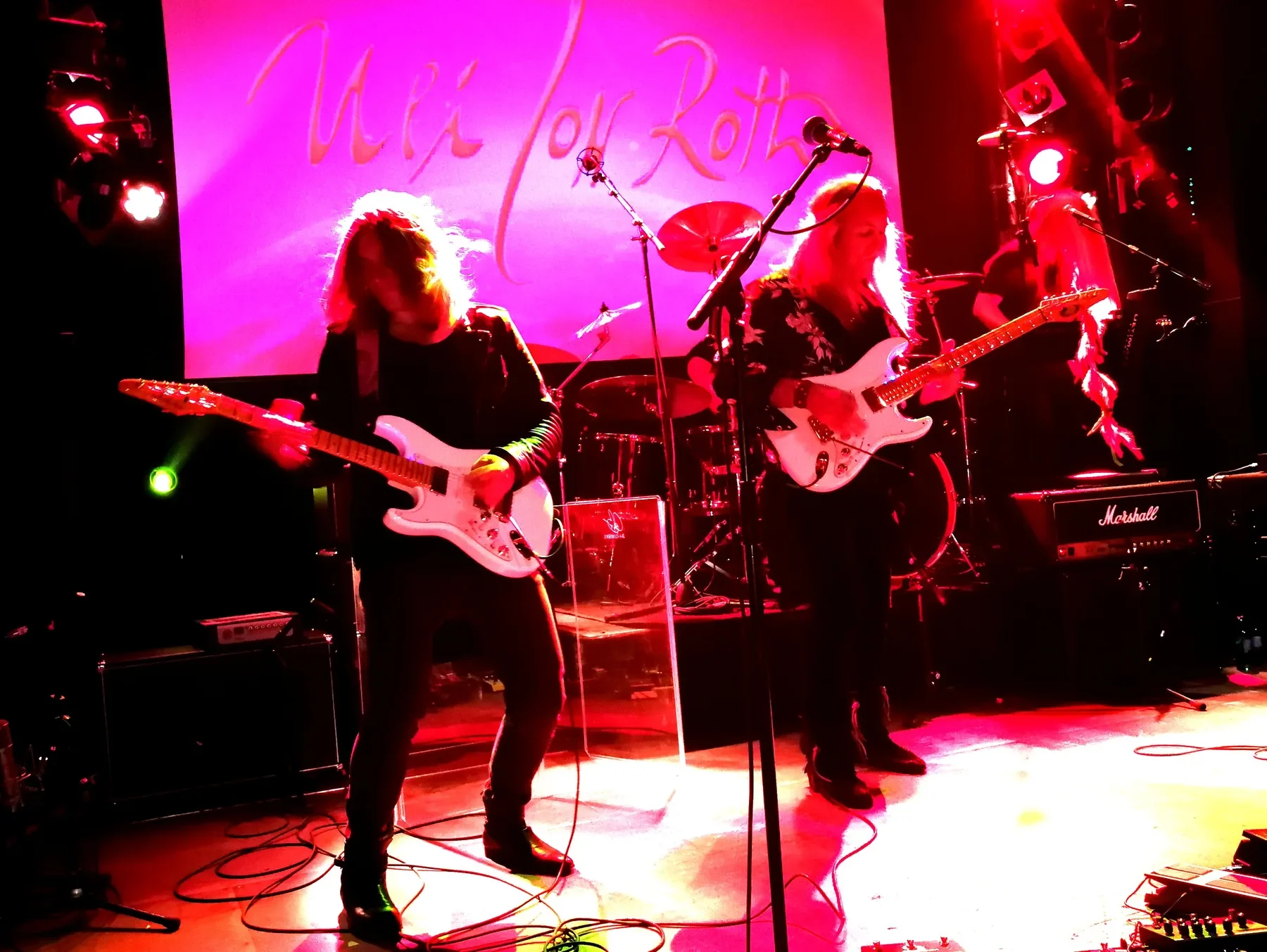 Uli Jon Roth y otro guitarrista tocan Sky Strats blancas en un escenario con luces rosas