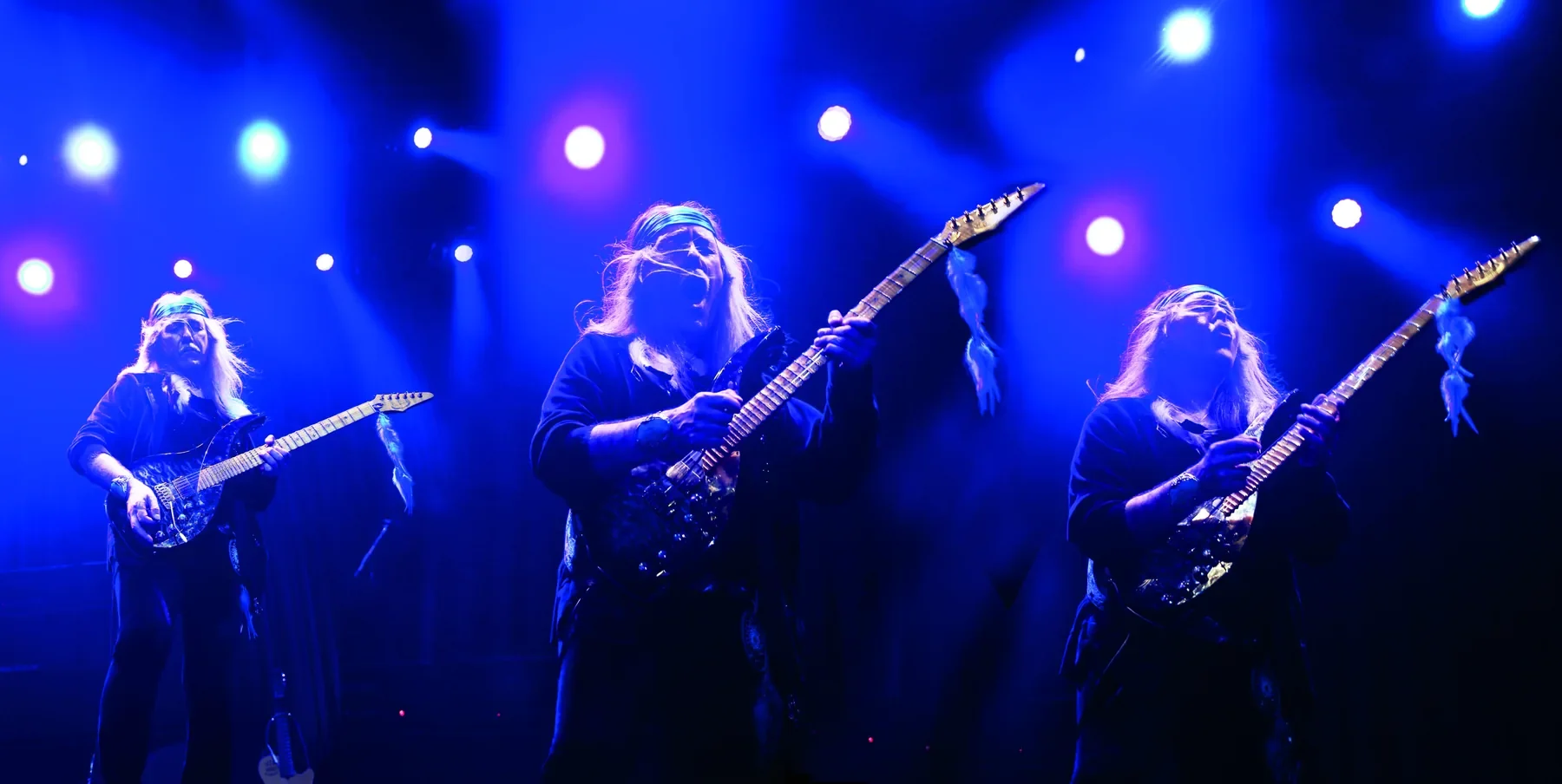 Tres guitarristas bajo focos azules en el concierto de Tokyo Tapes Revisited de Uli Jon Roth