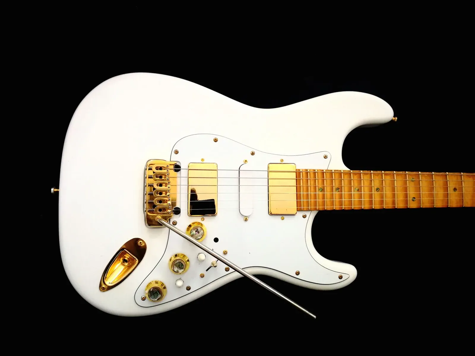 Cuerpo blanco de la Sky Super Strat sobre fondo negro: dos humbuckers dorados, una single coil blanca en el centro, puente de trémolo dorado y mandos rematados en nácar