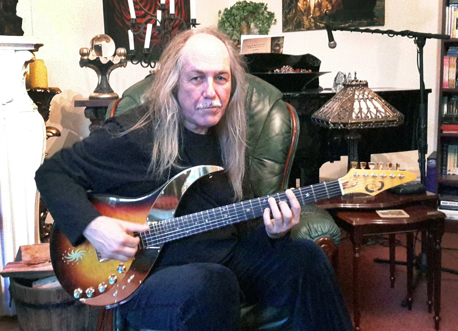 Uli Jon Roth sentado en un sillón, en casa, con una Sky Guitar sobre las piernas