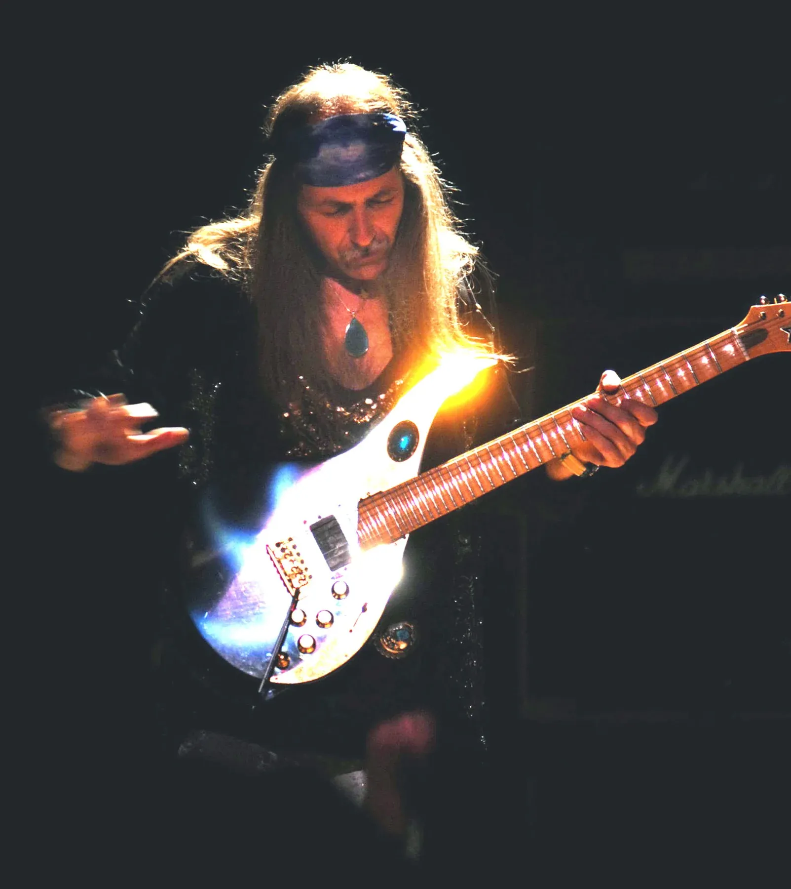 Uli Jon Roth tocando una Sky Guitar blanca sobre un fondo oscuro